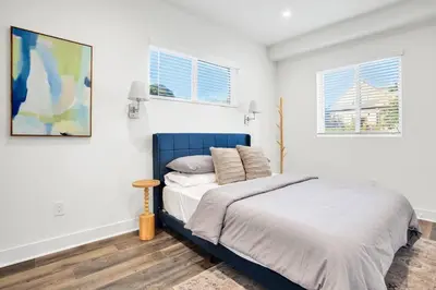 a bedroom with a blue bed and two windows at Fresh & New Downtown LA Condo! in Los Angeles