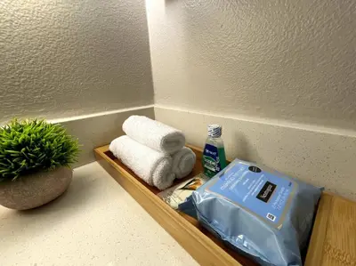 a shelf with towels and a bag of toothpaste and a plant at Cozy 2 Bedroom 2 Bathroom Condo with Pool, Gym, Spa in Los Angeles