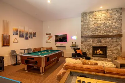 a living room with a pool table and a stone fireplace at 37 - Foxy Farm Ranch home in Big Bear Lake