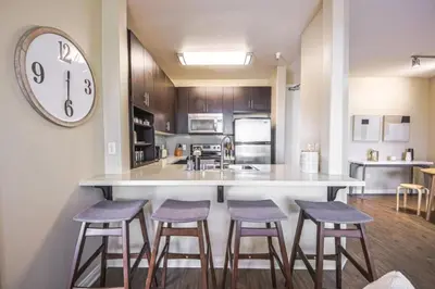 a kitchen with three bar stools and a clock on the wall at Marina del Rey 2BR - Near LAX, Beach & Dining in Los Angeles