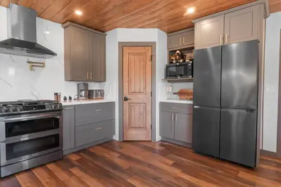 a kitchen with stainless steel appliances and wooden floors at The Lazy Bear - Indulge in breathtaking views of the expansive lake from this charming cabin. in Fawnskin
