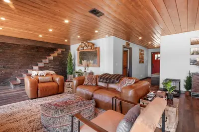 a living room with leather furniture and a wooden ceiling at The Lazy Bear - Indulge in breathtaking views of the expansive lake from this charming cabin. in Fawnskin