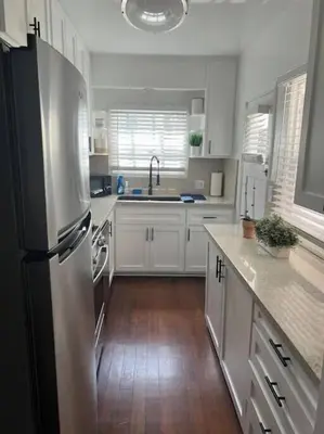a kitchen with white cabinets and a stainless steel refrigerator at Sea View, Flower Garden, AC, WD, Renovated in Hermosa Beach