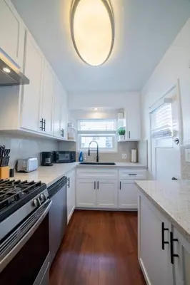 a kitchen with white cabinets and a sink and a stove at Sea View, Flower Garden, AC, WD, Renovated in Hermosa Beach