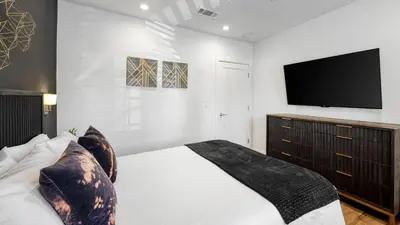 a bedroom with a bed and a flat screen tv at 5 Units in Heart of Hollywood Remodeled Art Deco Pink Revival by AvantStay in Los Angeles