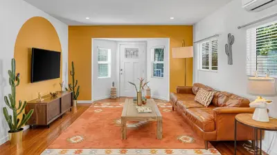 a living room with a brown couch and a tv at 5 Units in Heart of Hollywood Remodeled Art Deco Pink Revival by AvantStay in Los Angeles