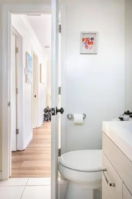 a white bathroom with a toilet and a hallway at 2min2Beach, Netflix, AC, WD,15min2LAX, Fast Wifi in Hermosa Beach