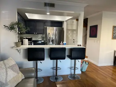 a kitchen with black cabinets and a counter with bar stools at Central LA GATED Community 4 beds home in Commerce