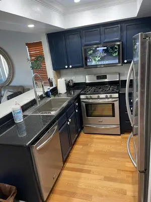 a kitchen with blue cabinets and a stainless steel refrigerator at Central LA GATED Community 4 beds home in Commerce
