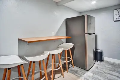 a bar with white stools and a refrigerator at Ventura Downtown Minutes to Beaches in Ventura