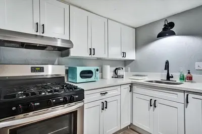 a kitchen with white cabinets and a stove top oven at Ventura Downtown Minutes to Beaches in Ventura
