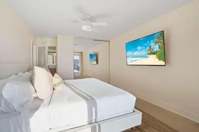 a bedroom with a white bed and a painting on the wall at Aquamarine Best View in Malibu by Stay Awhile Villas in Malibu Beach
