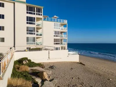 a building on the beach next to the ocean at Aquamarine Best View in Malibu by Stay Awhile Villas in Malibu Beach