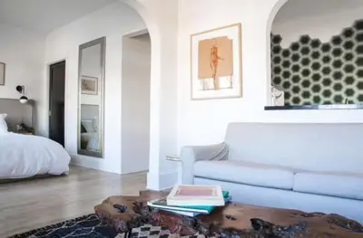 a white living room with a couch and a bed at Hotel Covell in Los Angeles