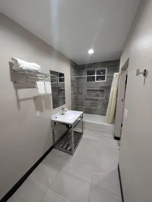 a white bathroom with a sink and a shower at Star Inn Hotel in Maywood