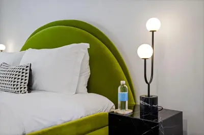 a bed with a green headboard with a bottle on a night stand at The Elvis Villa by Stay Awhile Villas in Los Angeles