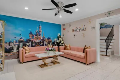 a living room with pink couches and a disney mural at Disneyland Oasis by OC Adventure Homes in Cypress