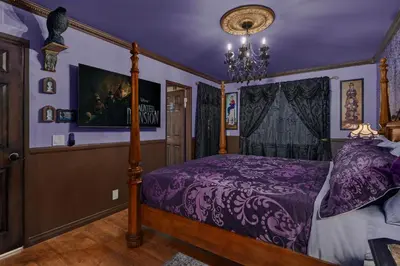 a bedroom with a bed with purple sheets and a chandelier at Disneyland Oasis by OC Adventure Homes in Cypress