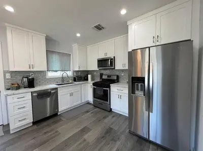 a kitchen with white cabinets and a stainless steel refrigerator at Adorable 2BR-2BA House with EV & Free Parking and Family Friendly in Los Angeles in Los Angeles