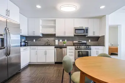 a kitchen with white cabinets and a wooden table at Spacious 2BD 2BA with Huge Balcony, Near Venice Beach & Fun! in Marina del Rey