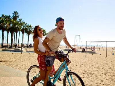 a man and a woman riding a bike on the beach at Well-Located 3BR Near SoFi Stadium & LAX in Los Angeles