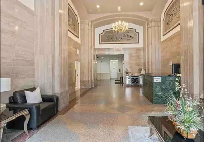 a lobby with a black leather couch and a chandelier at Iconic Heart of DTLA Loft with Rooftop Pool Jacuzzi Gym in Los Angeles