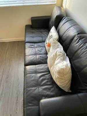 a black leather couch with two pillows on it at Cozy spot in Koreatown in Los Angeles