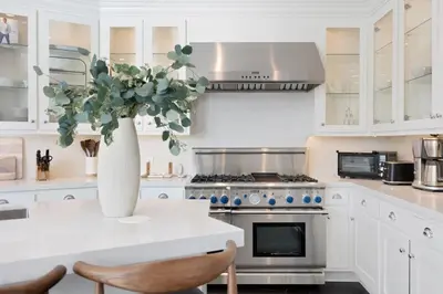 a white kitchen with a vase of flowers on a counter at Chateau Beverly Hills by Stay Awhile Villas in Los Angeles