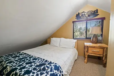 a bedroom with a bed and a table with a window at Smo Haus- Located in the quiet area of Big Bear City, with mountain views. in Big Bear City