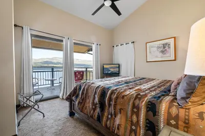 a bedroom with a bed and a balcony with a view at Shores Lakefront Condo - Walk to Village, Lake Views, Deck with BBQ in Big Bear Lake