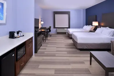 a hotel room with two beds and a desk and a table at Holiday Inn Express Hotels & Suites Loma Linda by IHG in Loma Linda