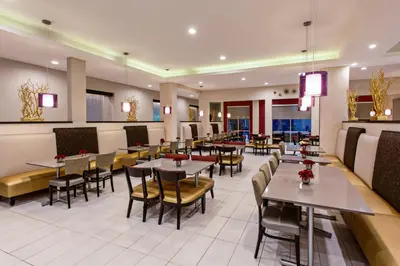 a dining room with tables and chairs in a restaurant at Holiday Inn Express & Suites Anaheim Resort Area by IHG in Anaheim