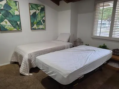 two beds in a room with white walls at Westside Retreat w Yard, Grill, Hot Tub, Near Sofi Stadium, LAX, and the Beach in Los Angeles