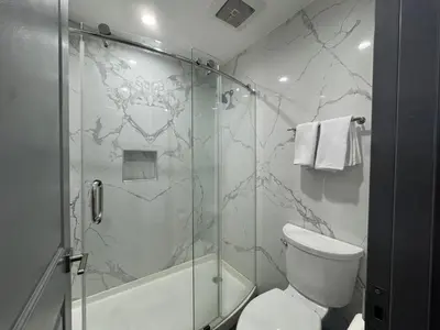a bathroom with a toilet and a glass shower at Bronco Motel South Central in Los Angeles