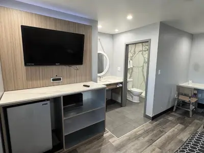 a bathroom with a flat screen tv on a wall at Bronco Motel South Central in Los Angeles