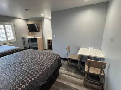 a bedroom with a bed and a desk and a table at Bronco Motel South Central in Los Angeles