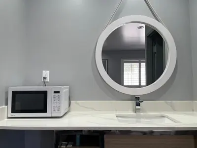 a microwave sitting on a bathroom counter with a mirror at Bronco Motel South Central in Los Angeles