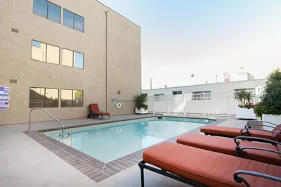 a swimming pool with two chairs next to a building at Blueground N Hollywood Gym Pool nr shops LAX-515 in Los Angeles