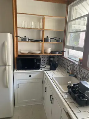 a kitchen with white cabinets and a sink and a refrigerator at Hancock weho in Los Angeles