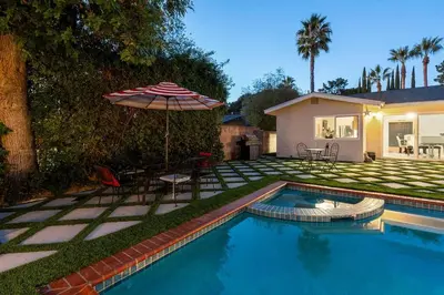 a swimming pool with an umbrella and a house at Luxury 4BD and 3BA in Topanga Oasis with Pool, Spa and Cabana in Glenview