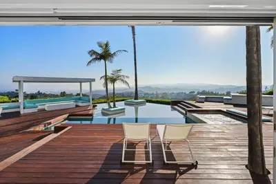two chairs on a deck with a pool and palm trees at Crest Estate by Stay Awhile Villas in Los Angeles