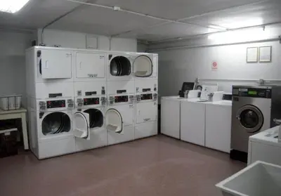 a laundry room with three washer and dryers at Chambre de Bonne in Downtown Long Beach in Long Beach