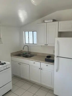 a white kitchen with a sink and a refrigerator at Santa Monica Stays in Los Angeles