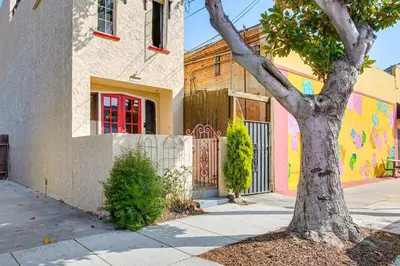 a tree in front of a building with a gate at 1 Mi to Ocean! Home with Rooftop Deck in Long Beach in Long Beach