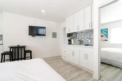 a white bedroom with a bed and a mirror at Sunny Studio in the Heart of Venice Beach - #5 in Los Angeles