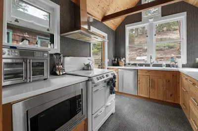 a kitchen with white appliances and wooden cabinets at Mountain Cottage - Hot Tub! Walk to Lake and National Forest Hiking Trails in Big Bear Lake