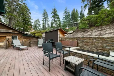 a wooden deck with chairs and a grill at Mountain Cottage - Hot Tub! Walk to Lake and National Forest Hiking Trails in Big Bear Lake