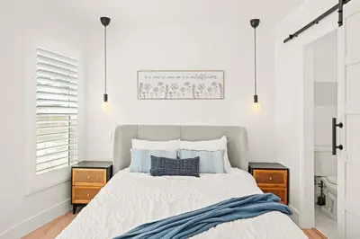 a white bedroom with a bed with blue pillows at Cozy Retreat Near Downtown - Perfect for Families in Long Beach
