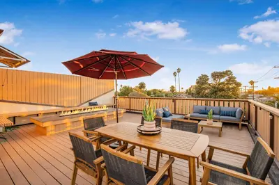 a wooden deck with a table and chairs and an umbrella at Cedar Loft Villa in Los Angeles