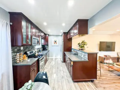 a large kitchen with wooden cabinets and a living room at Cozy 2BR Getaway with Pool, Close to SoFi - MKMD1 in Los Angeles